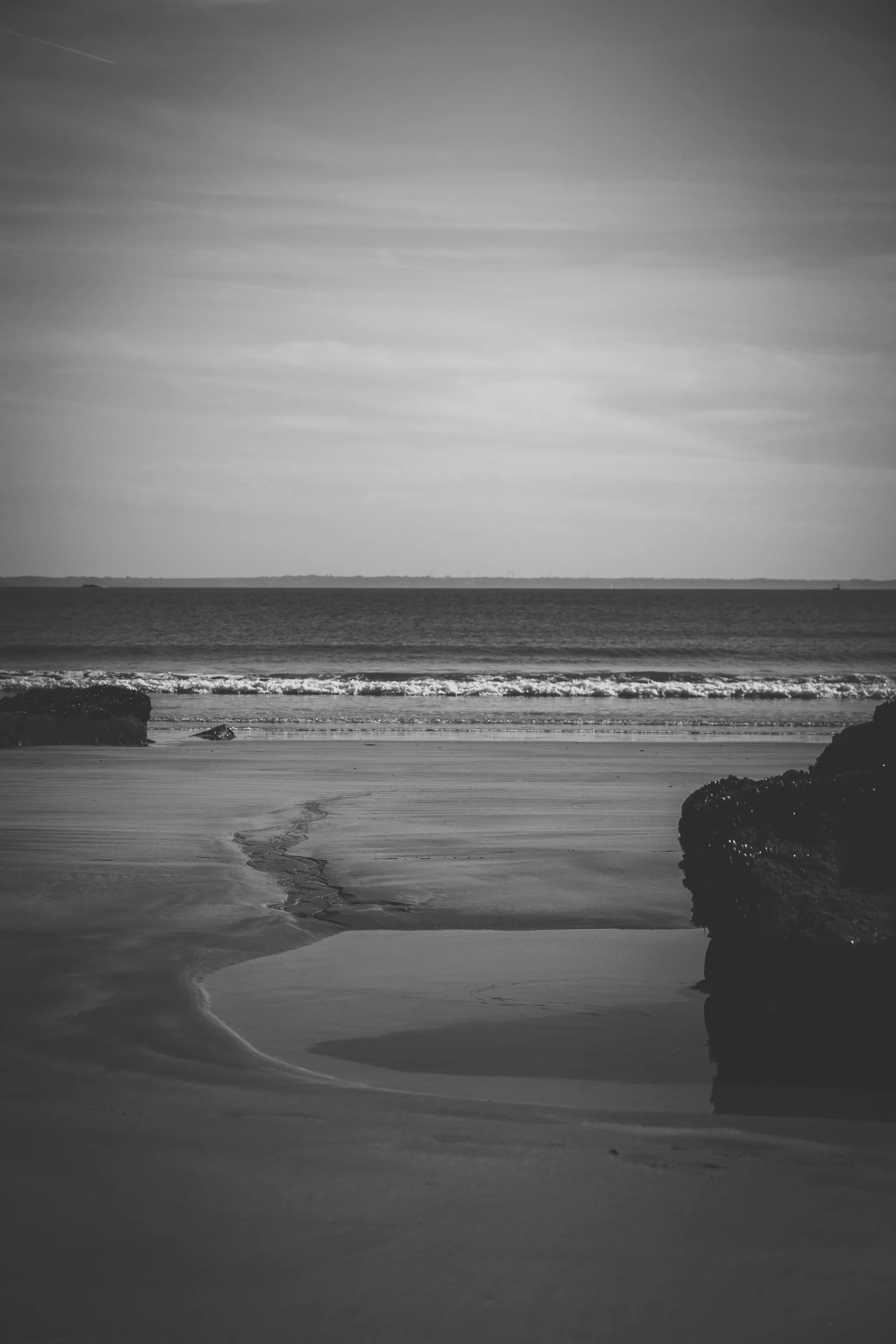 Tidal pool and rock on the beach at low tide, black and white