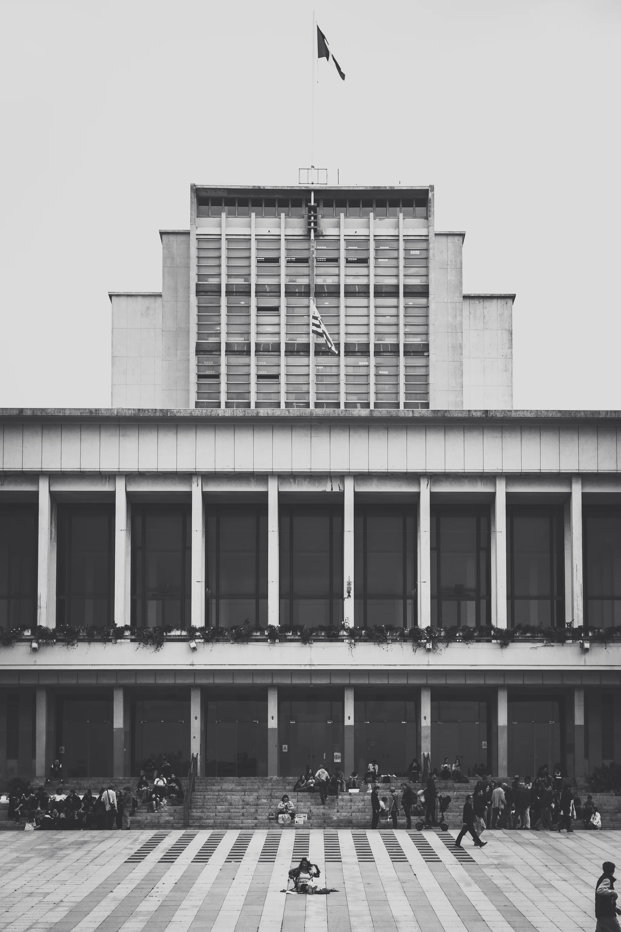 Brest city hall with its flag on the stepped tower, people on the steps of the square, black and white