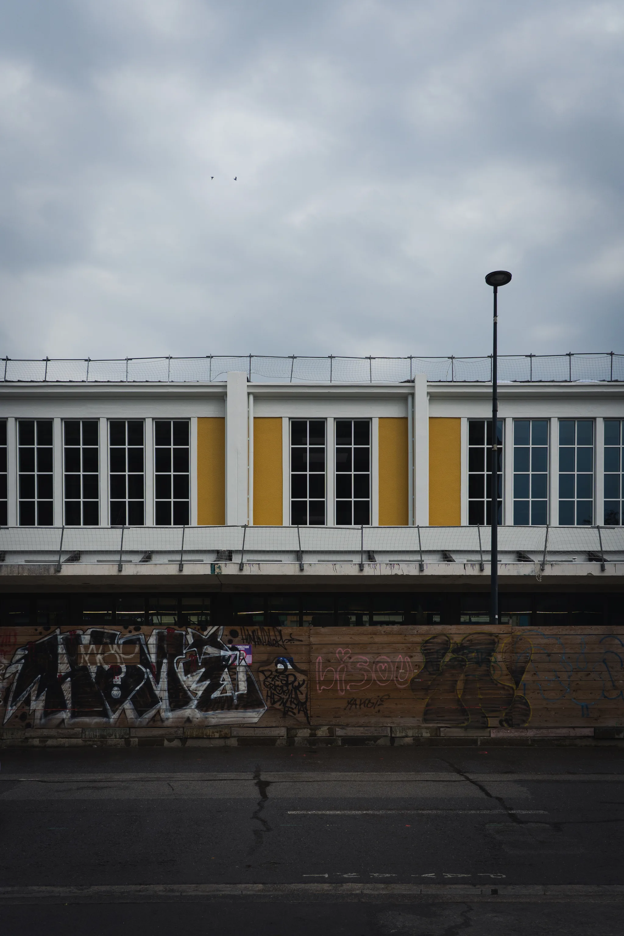Yellow and white market hall façade above a graffiti-covered wall