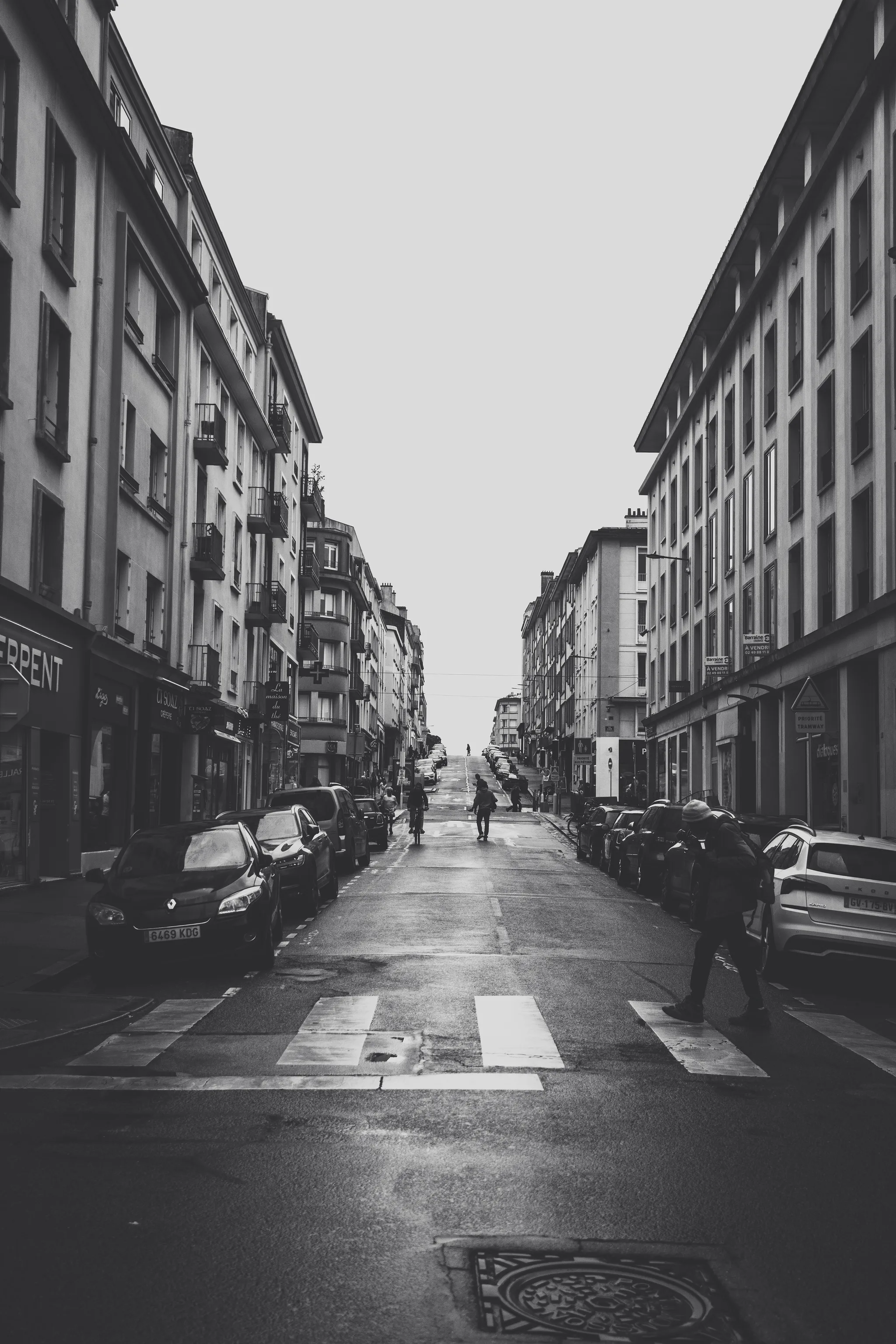 Long straight street of rebuilt apartment blocks running toward the sea, black and white