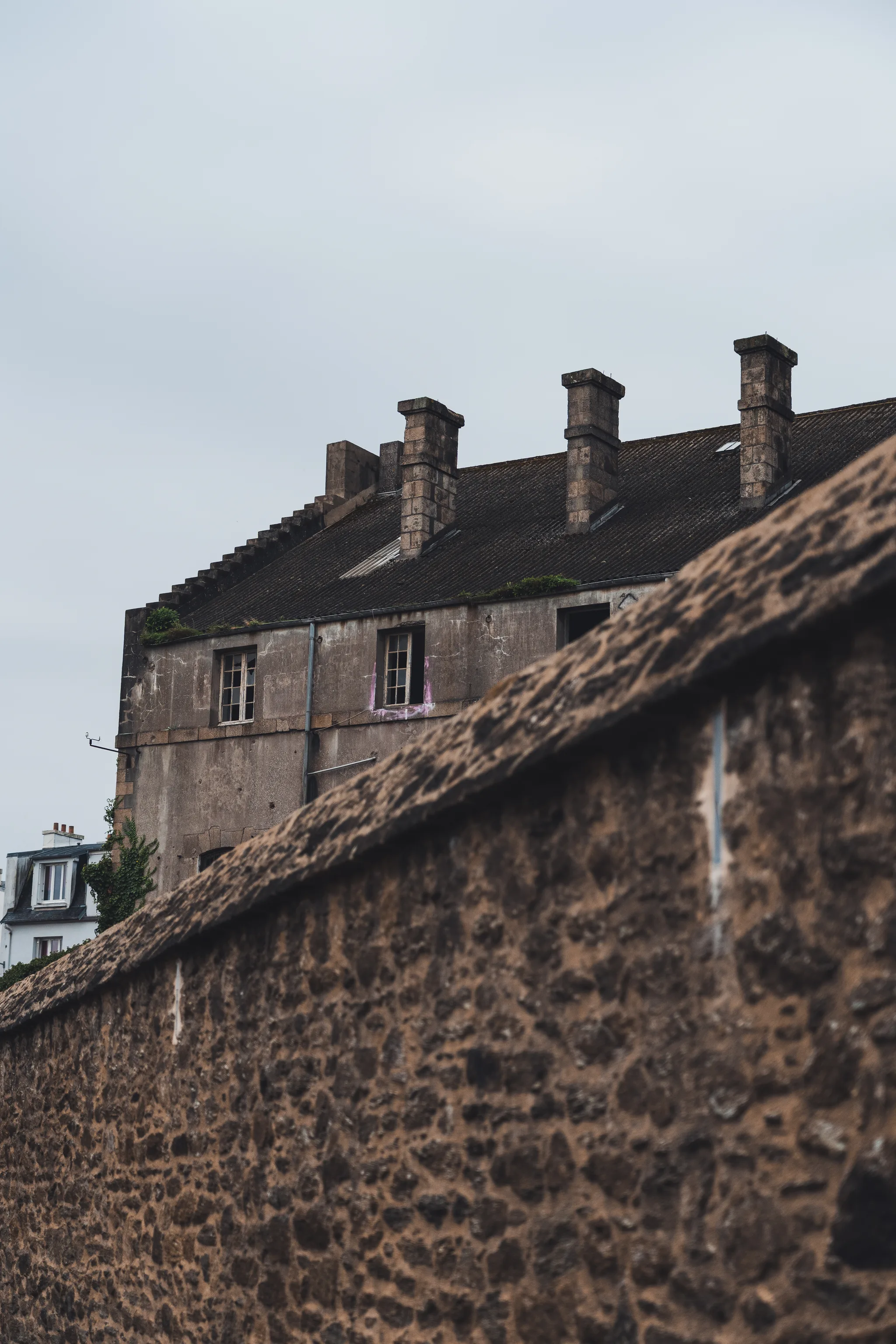 Old stone house with chimneys behind a rough stone wall