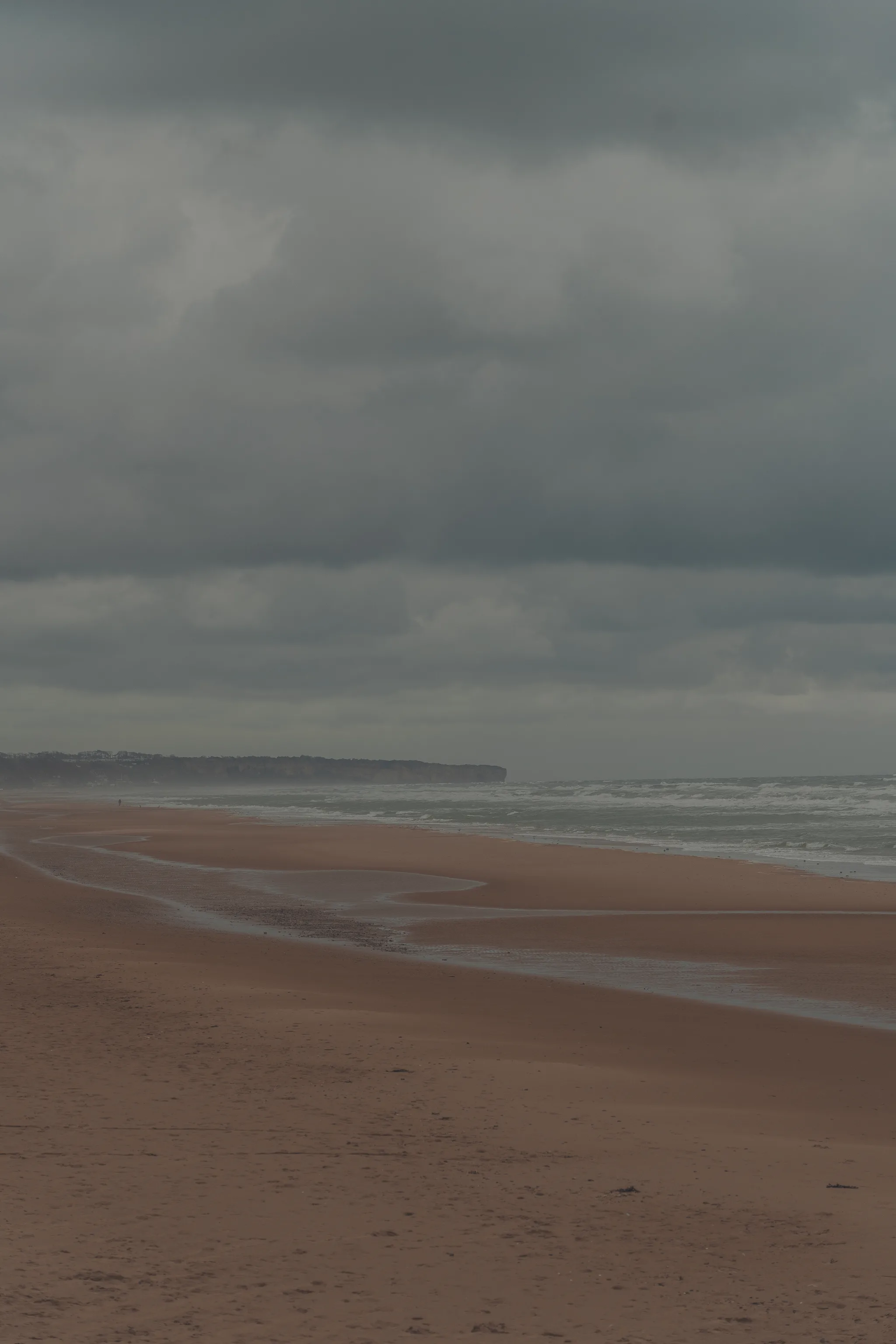 Sand ripples and the waterline under a grey evening sky