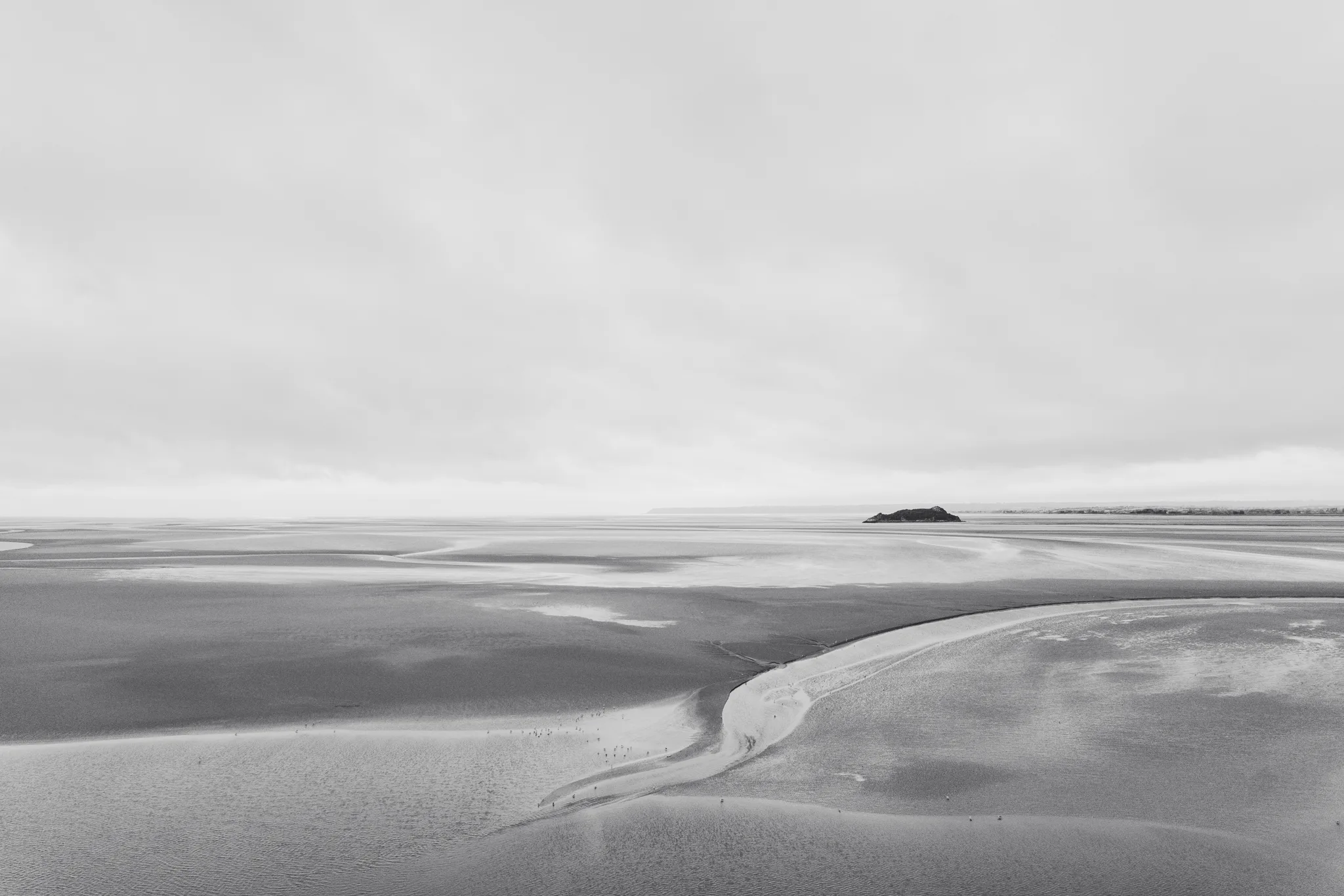 A winding tidal channel and Tombelaine on the horizon, black and white