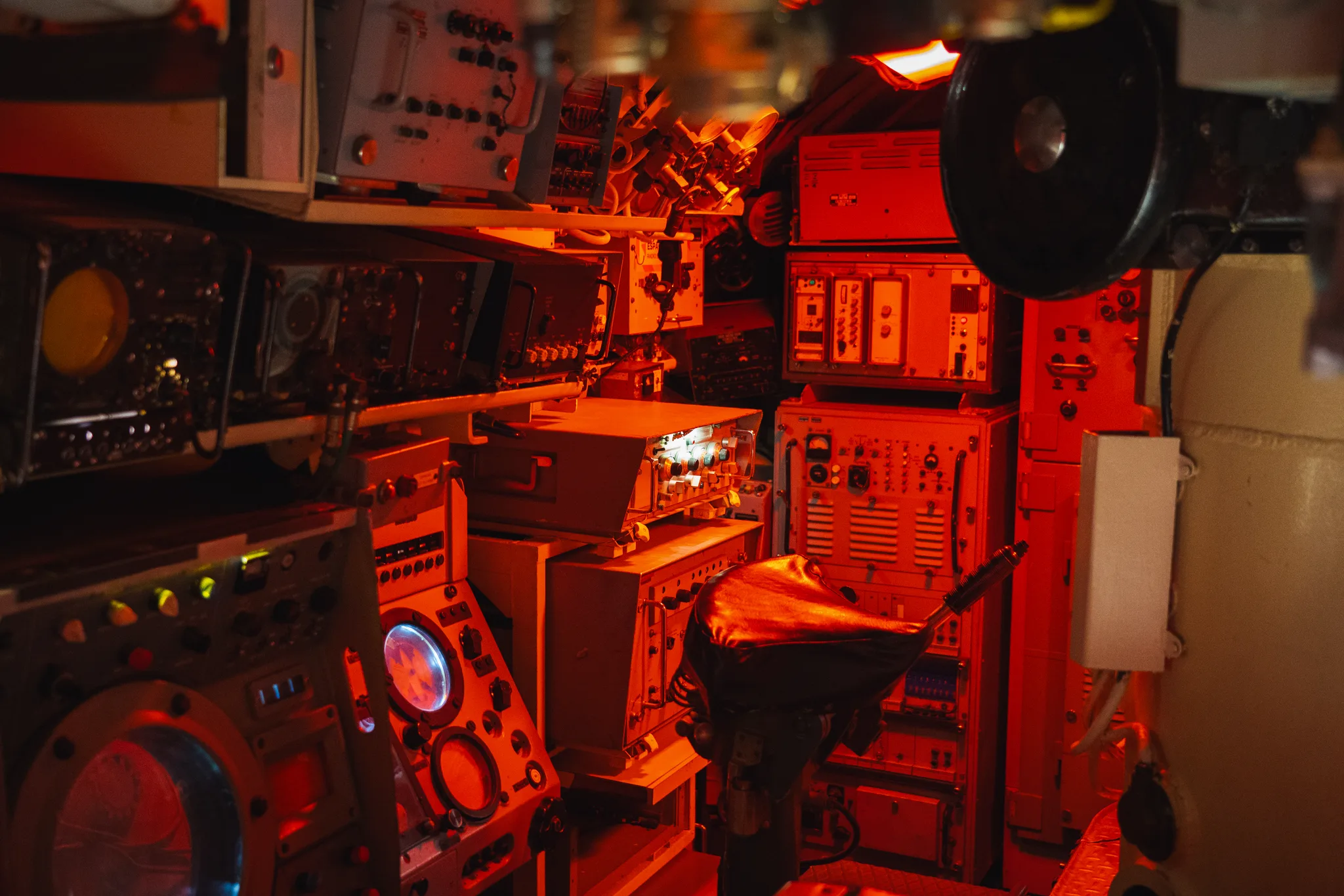 Control room of the submarine Flore in red light, dials, wheels and a periscope column