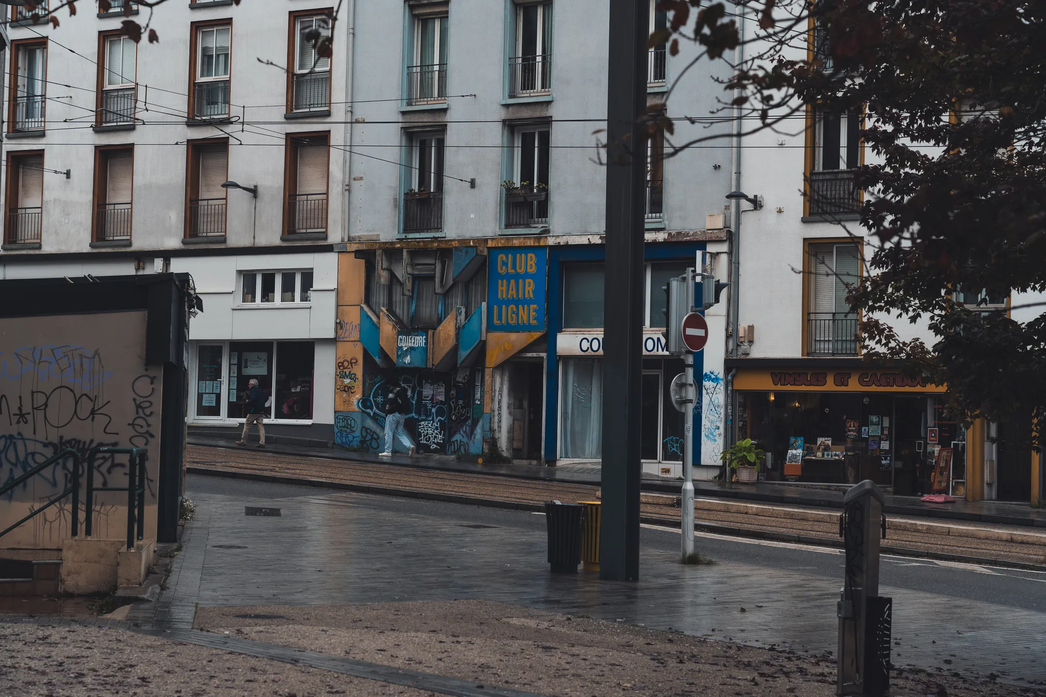Corner with a mural and a hair salon by the tram tracks on a wet day